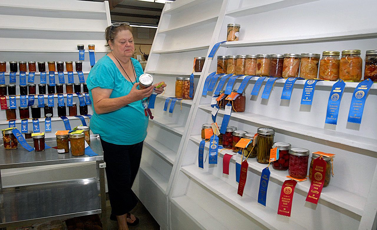 Home arts superintendent Renee Holt of Port Angeles arranges displays of canned fruits and vegetables Tuesday in preparation for the Clallam County Fair, which begins Thursday in Port Angeles. (Keith Thorpe/Peninsula Daily News)