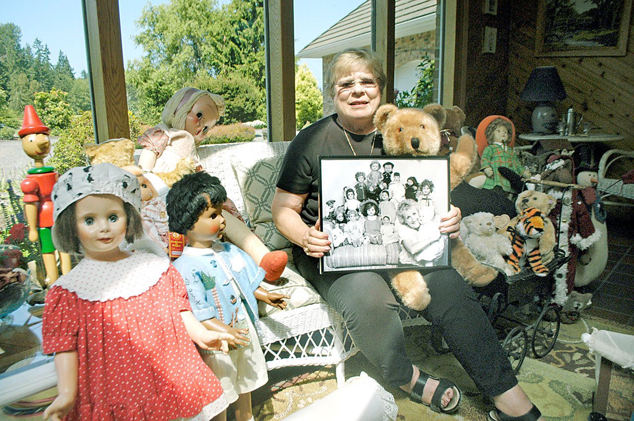 Irene Wyman, seen here at her home east of Port Angeles, has taken responsibility for the late Mari Andrus’ sizable doll and toy bear collection. Andrus is seen in the black and white photo held by Wyman. (Chris McDaniel/Peninsula Daily News)