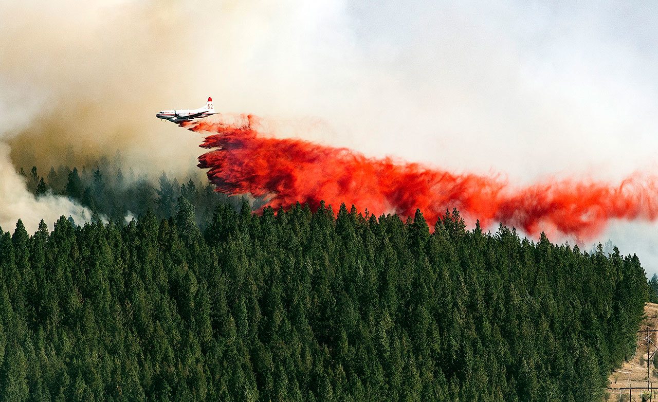A plane drops fire retardant on the north side of Beacon Hill on Sunday in Spokane. The fast moving wildfire is threatening structures as it moves in a northeasterly direction. (Colin Mulvany/The Spokesman-Review, via AP)