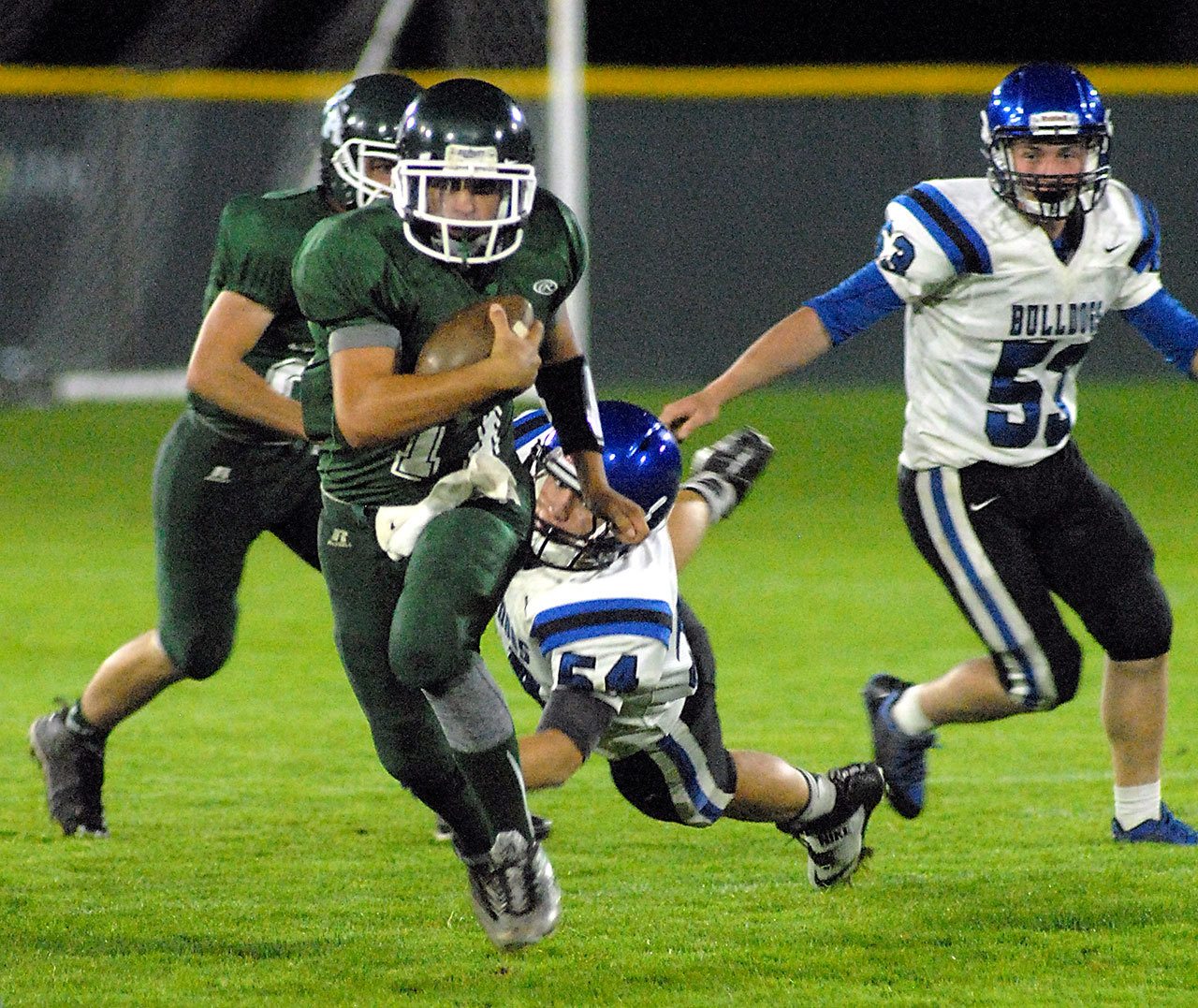 Keith Thorpe/Peninsula Daily News Port Angeles quarterback Matthew Warner, front, eludes the defense of North Mason’s Cody Myrick and Rick Miller, right, as Warner’s teammate Jarrett Burns provides backup.