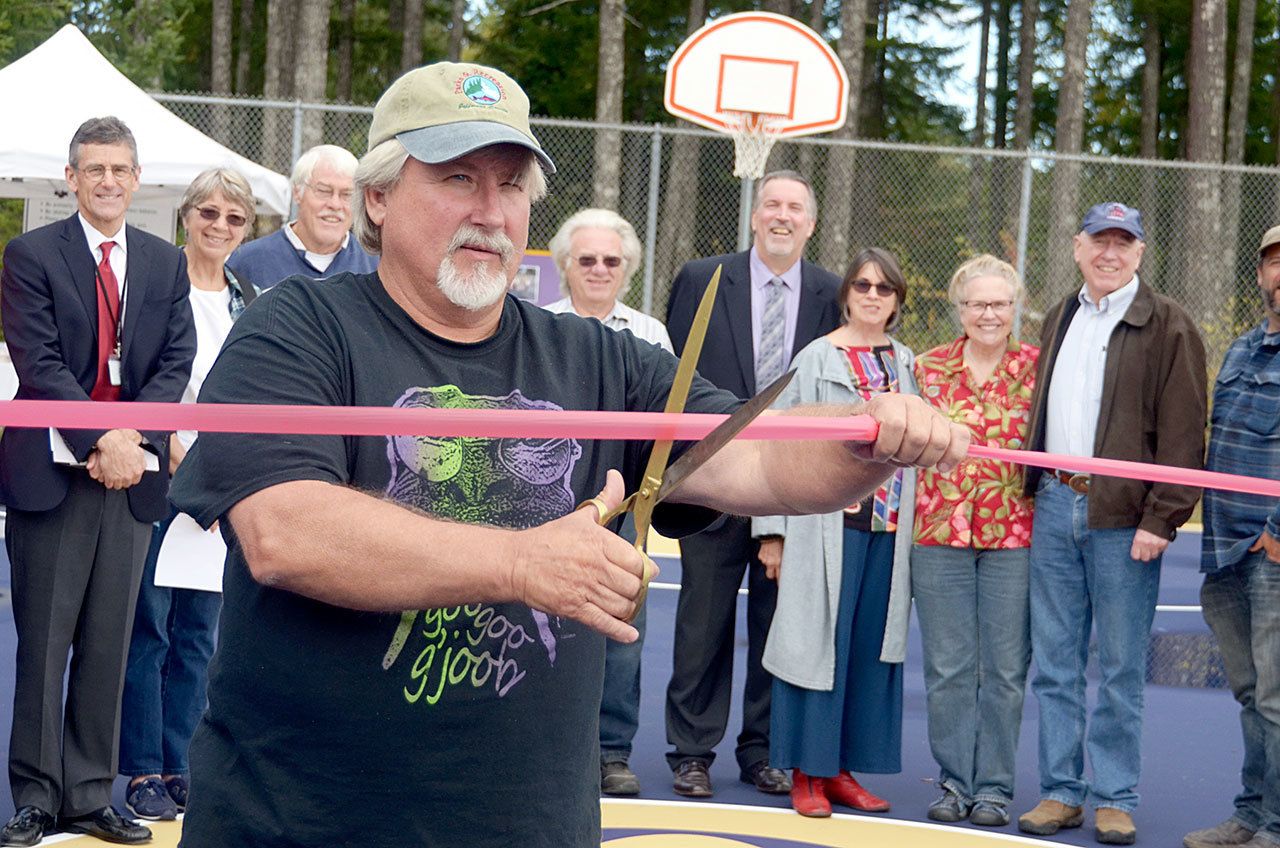 Clayton White, the community member who spearheaded the construction of the new courts, cuts the ribbon to celebrate the official opening of the new basketball and tennis courts at Quilcene Community Park. (Cydney McFarland/Peninsula Daily News)