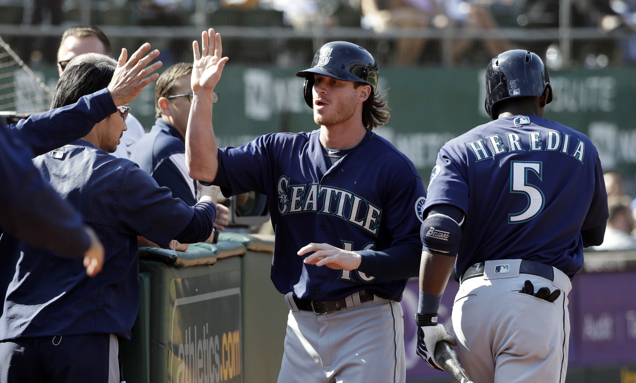 Seattle Mariners’ Ben Gamel, center, is high-fived in the dugout after scoring on a single by Ketel Marte during the ninth inning of a baseball game against the Oakland Athletics, Sunday, Sept. 11, 2016, in Oakland, Calif. (AP Photo/Marcio Jose Sanchez)