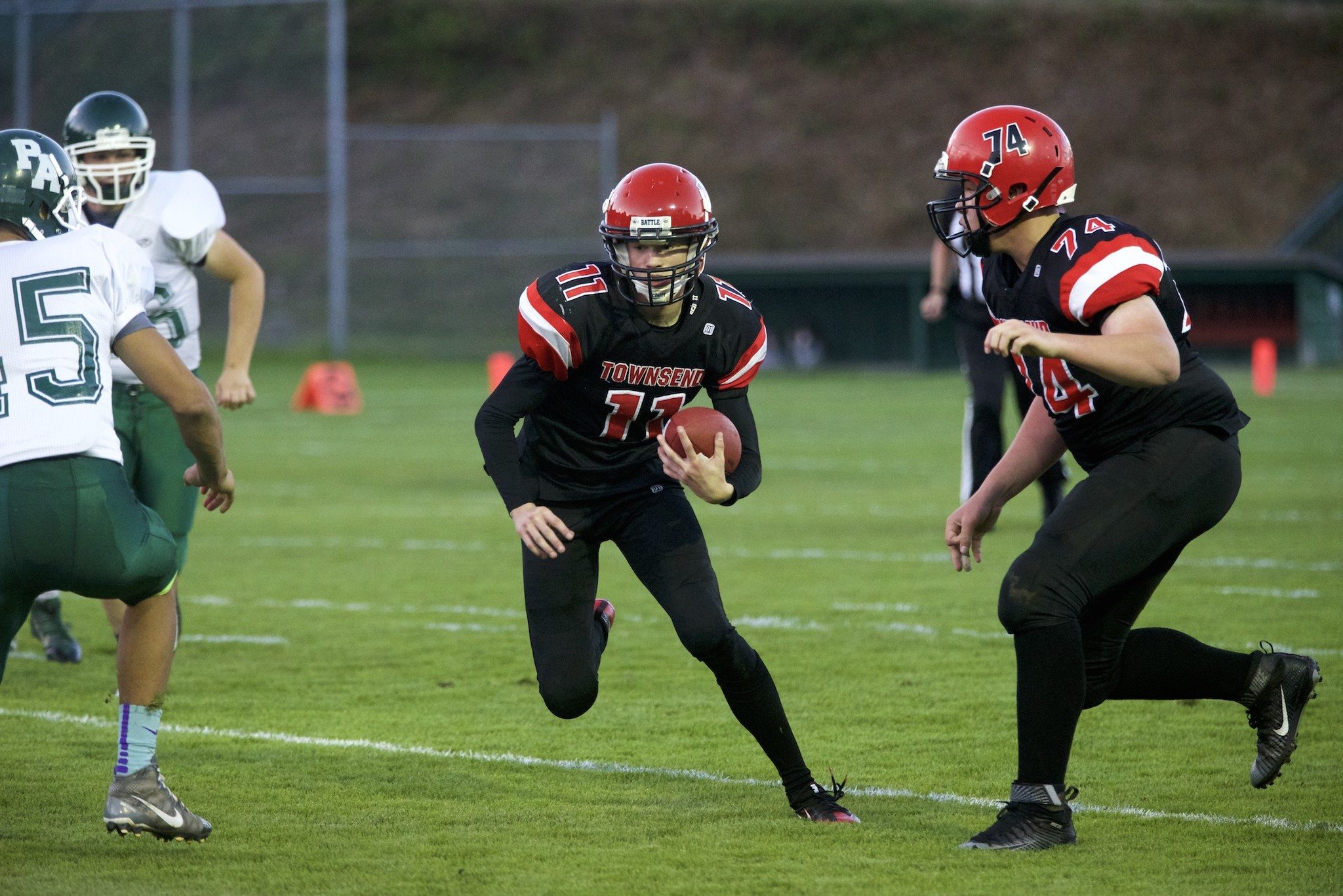 Steve Mullensky/for Peninsula Daily News Port Townsend ‘s Berkley Hill, with ball, plants a foot and dodges the tackles of a pair of Port Angeles Roughriders during a game played in Port Townsend on Thursday.