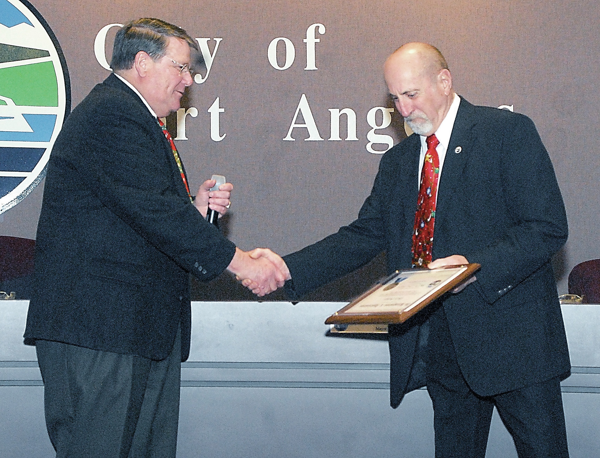 Port Angeles Mayor Dan Di Guilio, left, congratulates outgoing City Council Member and Deputy Mayor Don Perry at a City Council meeting. Perry was honored for his service as council member and for serving two years as deputy mayor. (Keith Thorpe/Peninsula Daily News)