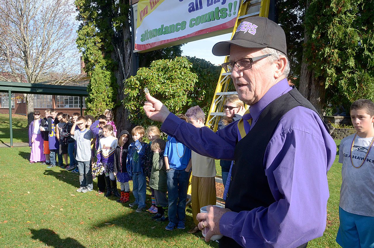 Quilcene Elementary School Principal Gary Stebbins awards students with perfect attendance with plastic gold coins that allow them to go to the front of any lunch line. (Cydney McFarland/Peninsula Daily News)