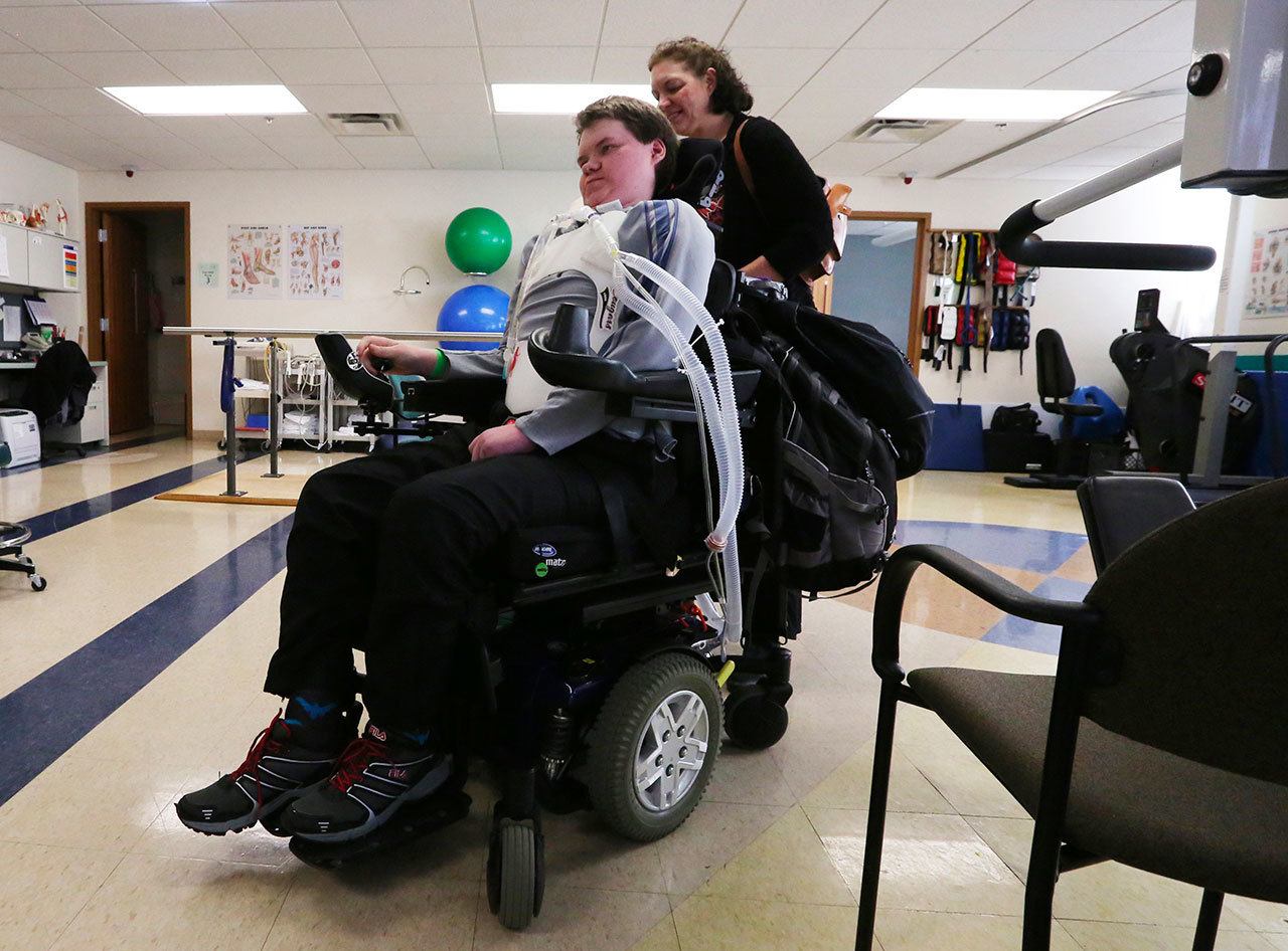 Heather Werdal helps her son Hayden after another session in the rehabilitation gym at Harrison Medical Center in Silverdale. As medical experts puzzle over the mysterious, polio-like illness that has afflicted eight Washington children this fall, Hayden, paralyzed by the same syndrome two years ago, struggles to recover. (Alan Berner/The Seattle Times via AP)