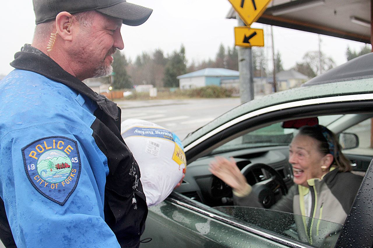 Judith Boissevain of Sequim reaches for her turkey from Forks Police Officer Donald Ponton. The turkeys were purchased by the Forks Police Foundation. (Christi Baron/Olympic Peninsula News Group)