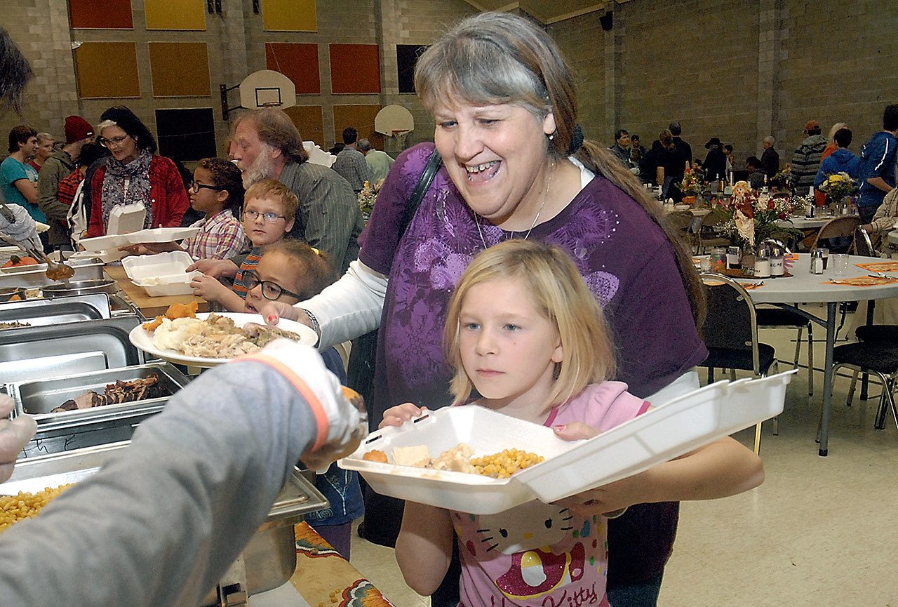 Lynette Schaner of Port Angeles and her granddaughter, Kalika Mulvaine, 10, go through the serving line during the annual community Thanksgiving dinner in the gym of Queen of Angels Catholic Church on Thursday in Port Angeles. (Keith Thorpe/Peninsula Daily News)