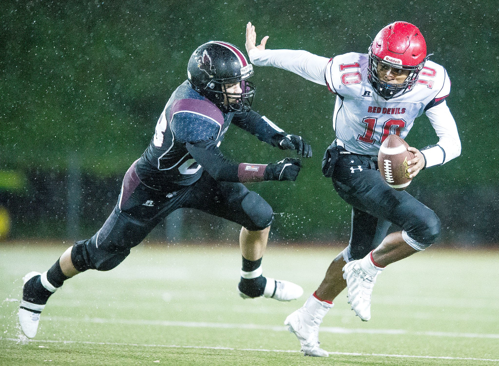 Neah Bay’s Rwehabura Munyagi, right, avoids the pass rush of Lummi’s Chance Poasa on Saturday, Nov. 26, at Everett Memorial Stadium in Everett.