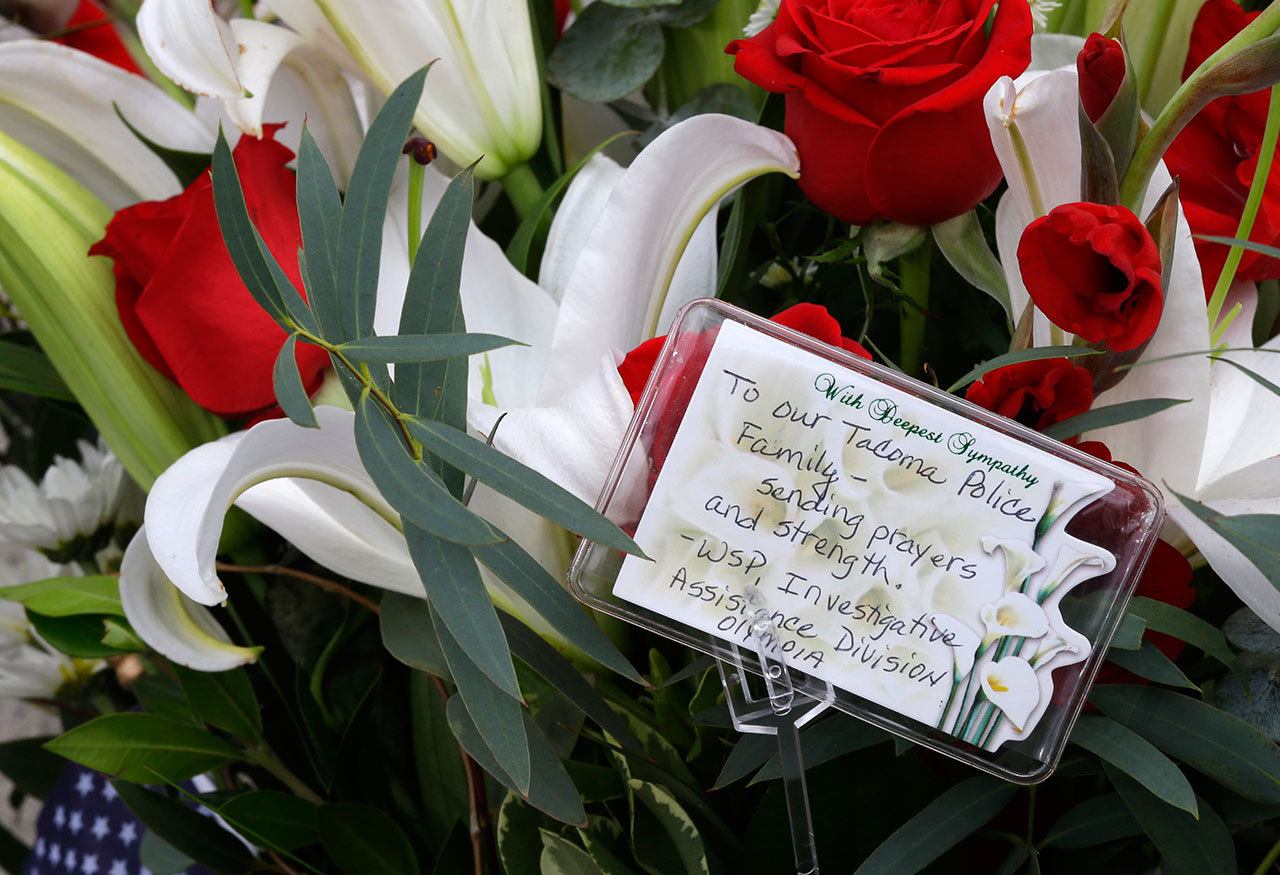 Flowers and a message from the Washington State Patrol Investigative Assistance Division are shown at a growing memorial outside the Tacoma Police Department headquarters Thursday in Tacoma. (Ted S. Warren/The Associated Press)