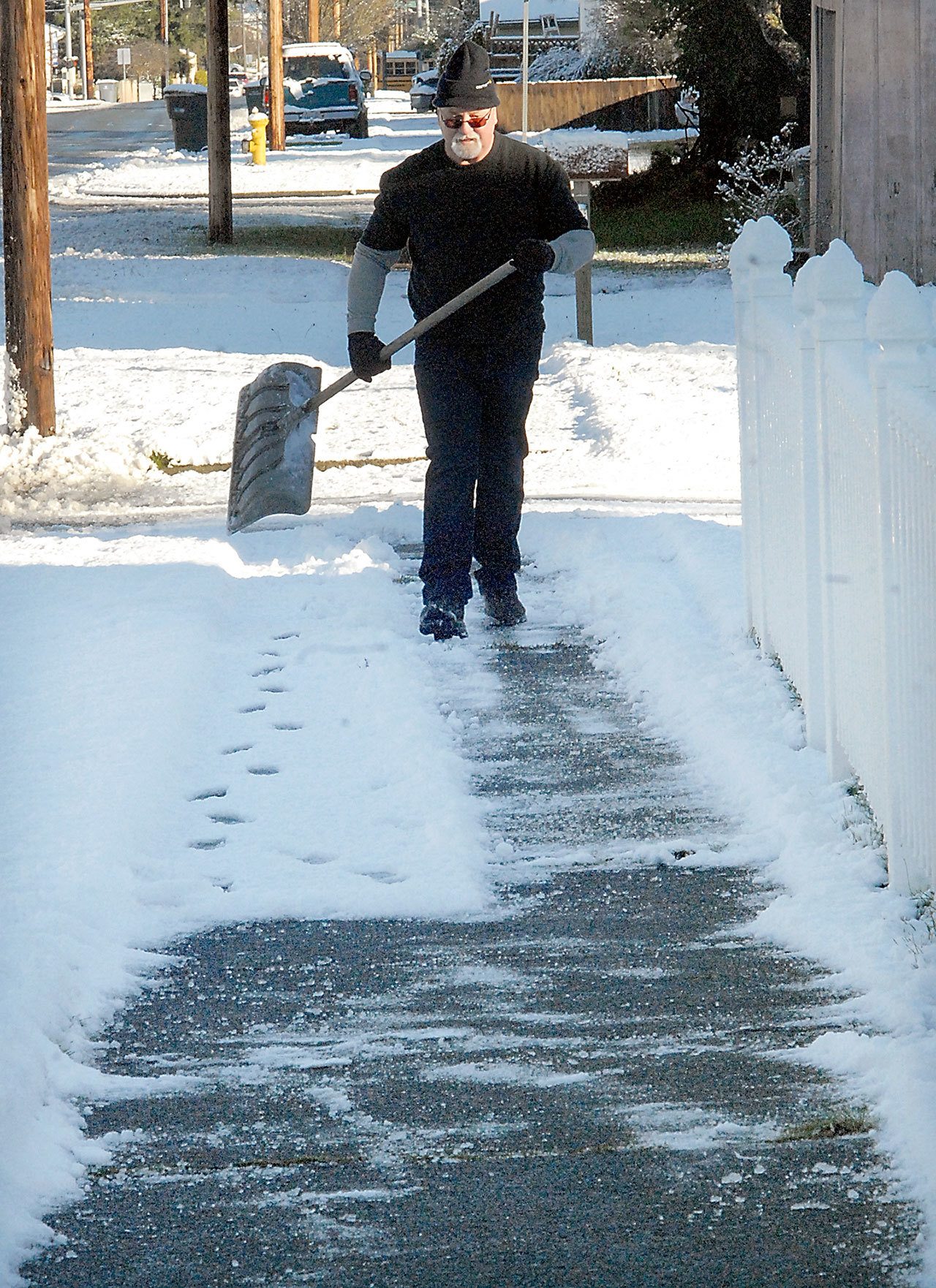 Sonny Carter of Port Angeles carries a snow shovel as he prepares to clear the sidewalk in the 1100 block of South Cherry Street in Port Angeles on Tuesday morning. (Keith Thorpe/Peninsula Daily News)