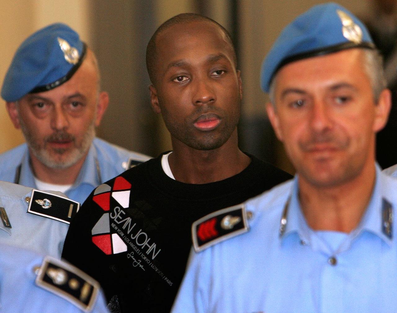 Rudy Hermann Guede from the Ivory coast, center, is escorted by Italian penitentiary police officers as he leaves Perugia’s court after a hearing in 2008 in central Italy. (The Associated Press)