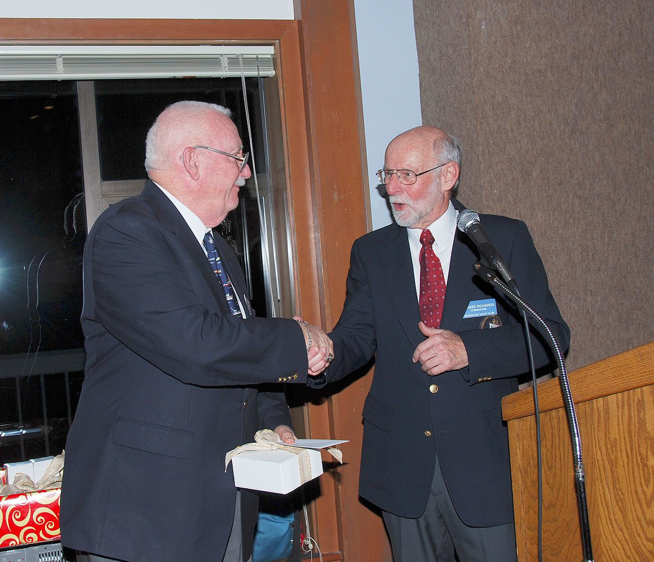 Ted Shanks, left, accepts his new role as Sequim Bay Yacht Club commodore from Durkee Richards.