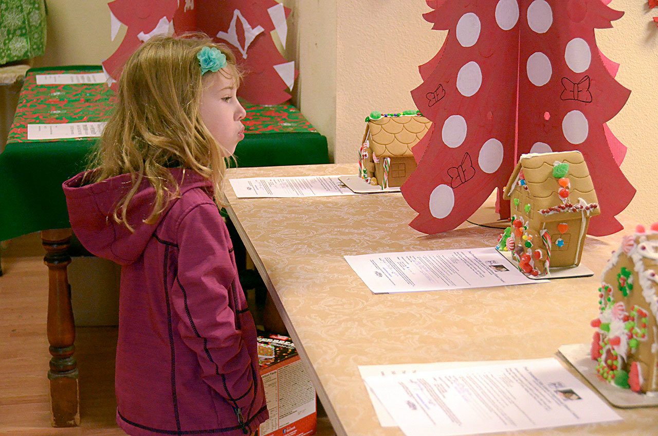 Hailey Owen examines some of the gingerbread houses submitted into this year’s competition. (Cydney McFarland/Peninsula Daily News)