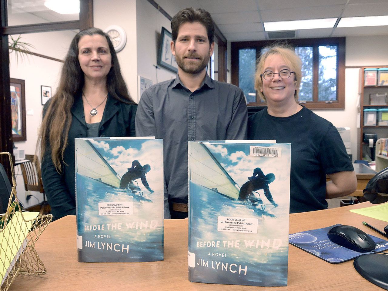 Port Townsend Public Library employees Jeanne Simmons, Keith Darrock and Kit Ward-Crixell stand with copies of “Before the Wind,” the 2017 Community Read book. (Cydney McFarland/Peninsula Daily News)