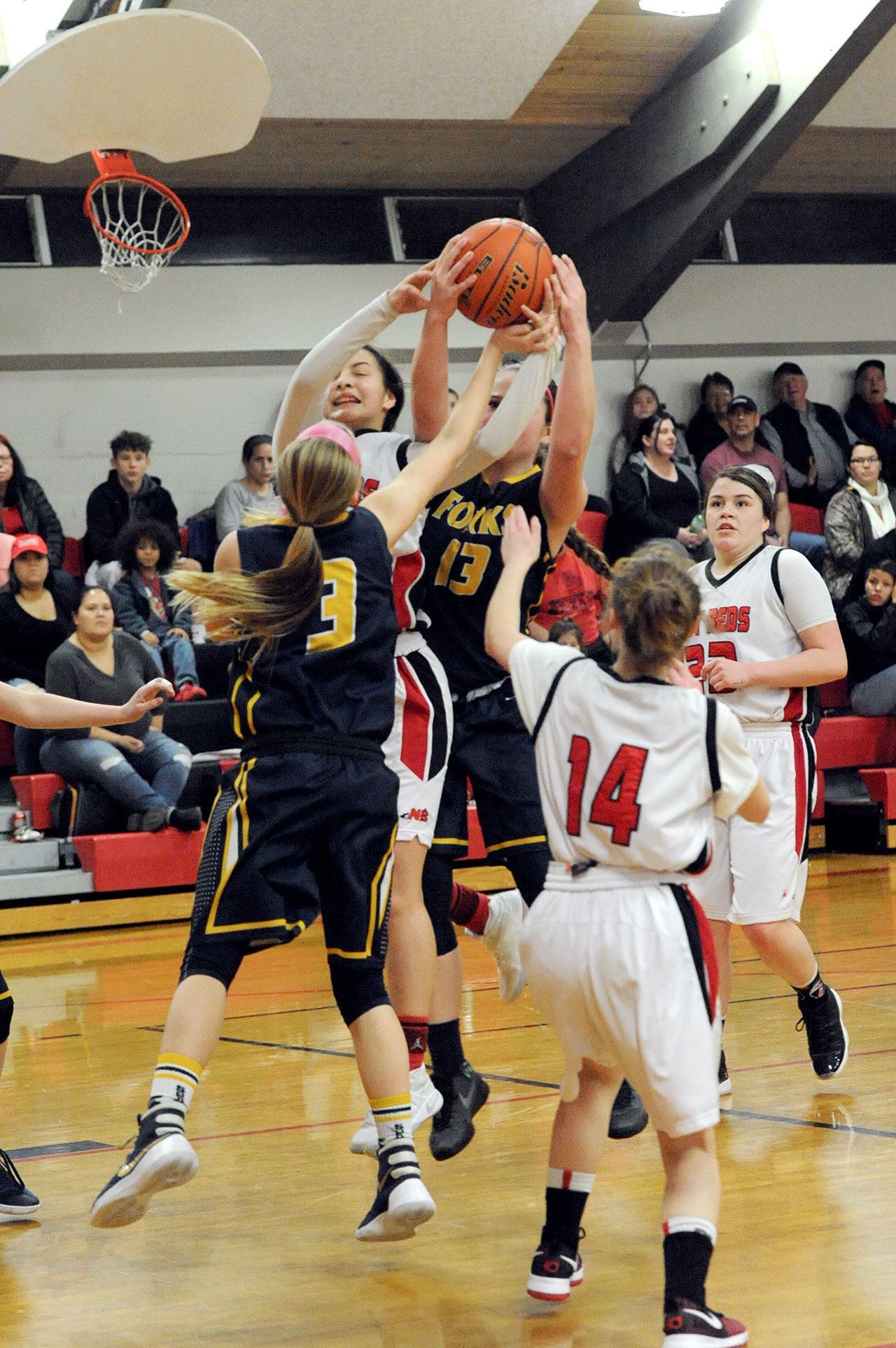 Lonnie Archibald/for Peninsula Daily News Forks’ Jayden Olson (3) and Rian Peters (13) vie for a rebound with Neah Bay’s Cei’J Gagnon, Cheyanna Svec (14) and Tristin Johnson (23).