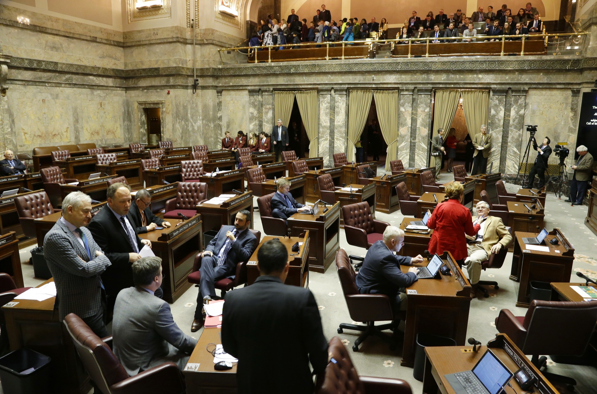 Democrats confer on the Senate floor as the Republican side sits empty during a recess Friday in Olympia. Senators were debating whether to vote on the “levy cliff” bill, which would delay a reduction in the amount of money school districts can collect though property taxes. (Ted S. Warren/The Associated Press)