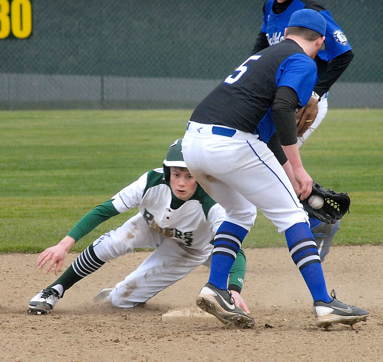 Keith Thorpe/Peninsula Daily News Port Angeles’ Joel Wood, left, holds onto second base after beating the throw to North Mason shortstop Donavan Shew and stealing the base during a loss to the Bulldogs at Volunteer Field.