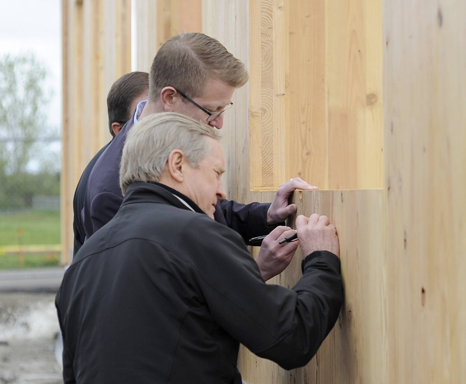 State Rep. Steve Tharinger, foreground, and U.S. Rep. Derek Kilmer put their signature on a cross-laminated timber modular building being built on the Greywolf Elementary School campus. (Michael Dashiell/Olympic Peninsula News Group)