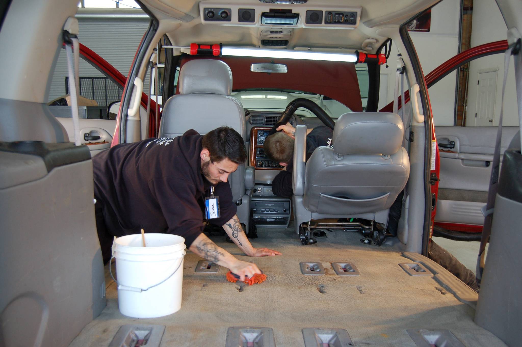 Employees of Skunkworks Auto Detailing & Body Repair Jesse Bailey, left, and Chris Babcock, right, volunteer to detail a donated van that will go toward Olympic Community Actions Programs’ senior nutrition program. (Erin Hawkins/Olympic Peninsula News Group)