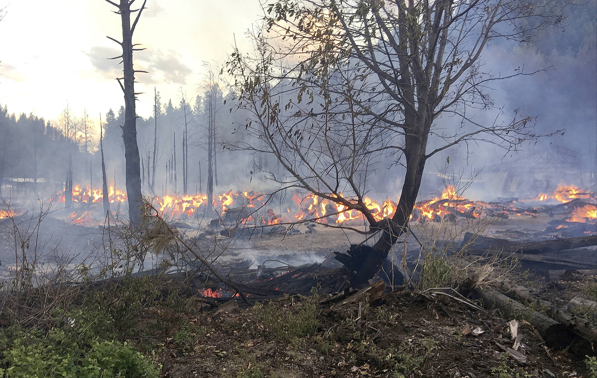 Ben Torkelson (2)/Chelan County Fire District 3 via AP                                In these Tuesday photos provided by Chelan County Fire District 3, logs burn near Leavenworth. The wildfire that started at an old log-storage site has prompted evacuation orders for homes and cabins at a popular Washington state hiking and skiing destination, officials said Wednesday.