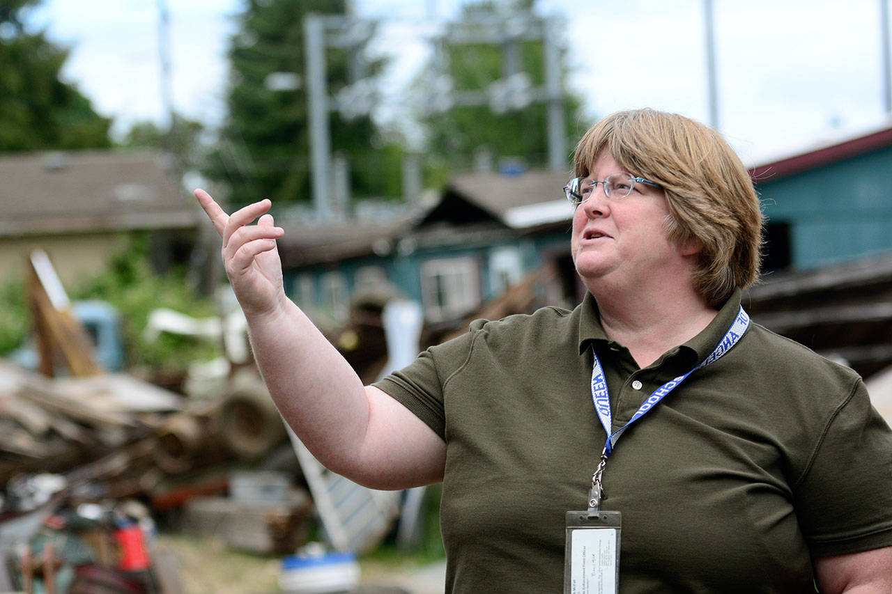 Barb McFall, Clallam County’s only code enforcement officer, chats with a homeowner cleaning his property. (Jesse Major/Peninsula Daily News)