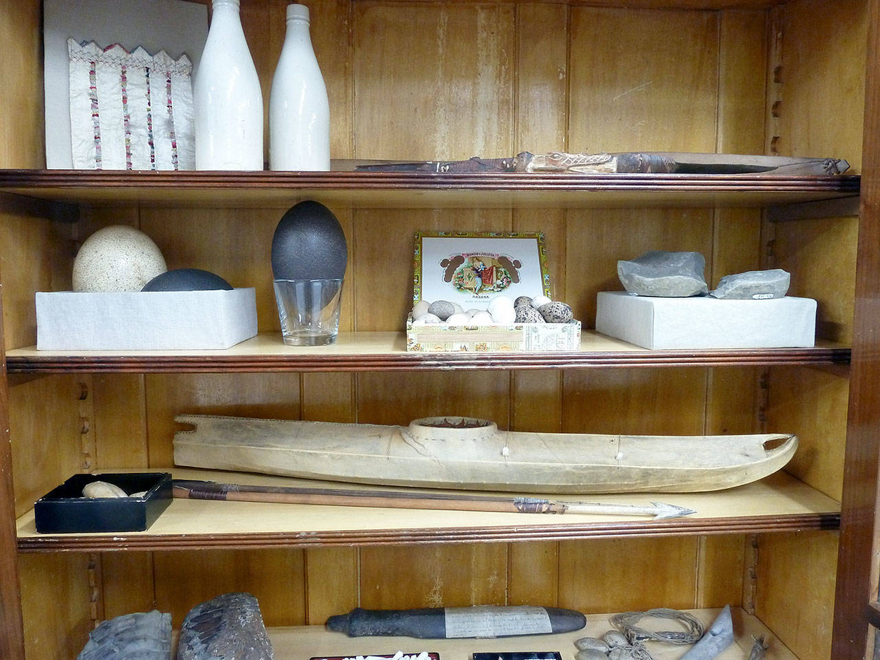 Cabinets of Curiosities contained any number and variety of interesting items. These shelves hold a scientifically cataloged egg collection, a Bering Strait kayak and stoneware beer bottles from Polk Marine Park, among other items. (Bill Tennent)