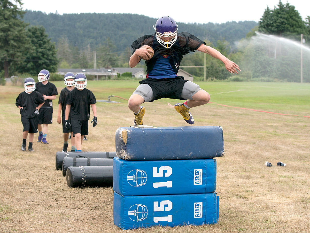 Quilcene’s Robert Comstock III shows his agility by leaping over foam pads during a preseason practice.                                Steve Mullensky/for Peninsula Daily News