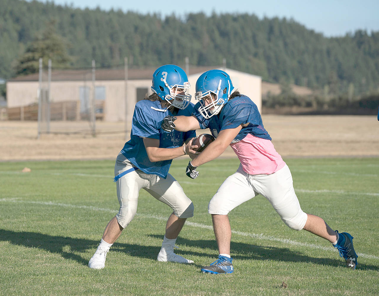 Steve Mullensky/for Peninsula Daily News                                Chimacum quarterback Cole Dotson, left, hands off to Logan Storm during a preseason practice. The Cowboys host Neah Bay tonight at Memorial Field in Port Townsend.