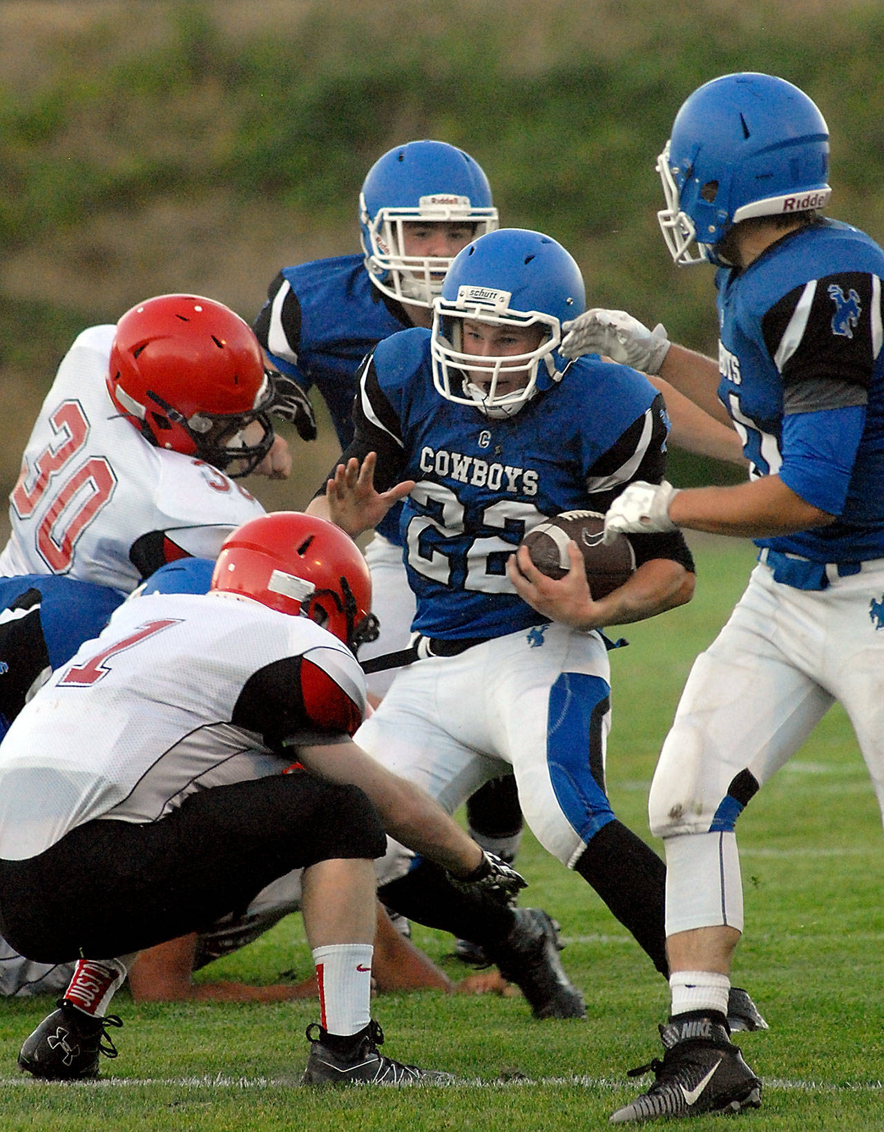 Chimacum’s Logan Shaw (22) tries to elude the defense of Neah Bay’s Daniel Kilmer (30), left, and Meric Soeneke (1) after receiving blocking assistance from teammates Ryan Caldwell (55), back, and Matthew Bainbridge (31), right, in the first quarter of Chimacum’s 21-6 victory.                                Keith Thorpe/Peninsula Daily News