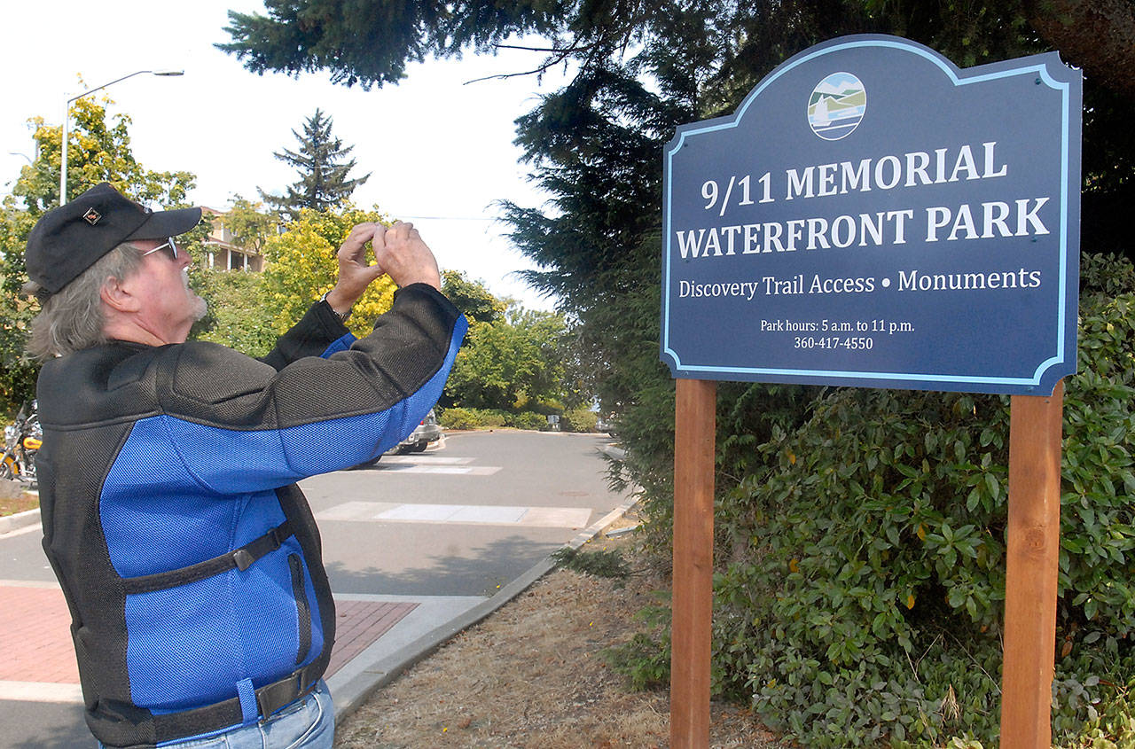 Alan Barnard, who was instrumental in the creation of a memorial to the victims of the terrorist attacks of Sept. 11, 2001, and for public safety personnel at Francis Street Park in Port Angeles, takes a photo of a newly installed sign denoting a name change to 9/11 Memorial Waterfront Park last month. (Keith Thorpe/Peninsula Daily News)