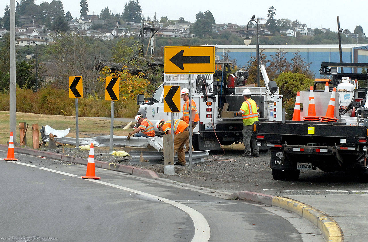 A Port Angeles Street Department crew removes a section of mangled guardrail near the Valley Creek Estuary along First Street after it was struck by a car early Friday morning. (Keith Thorpe/Peninsula Daily News)