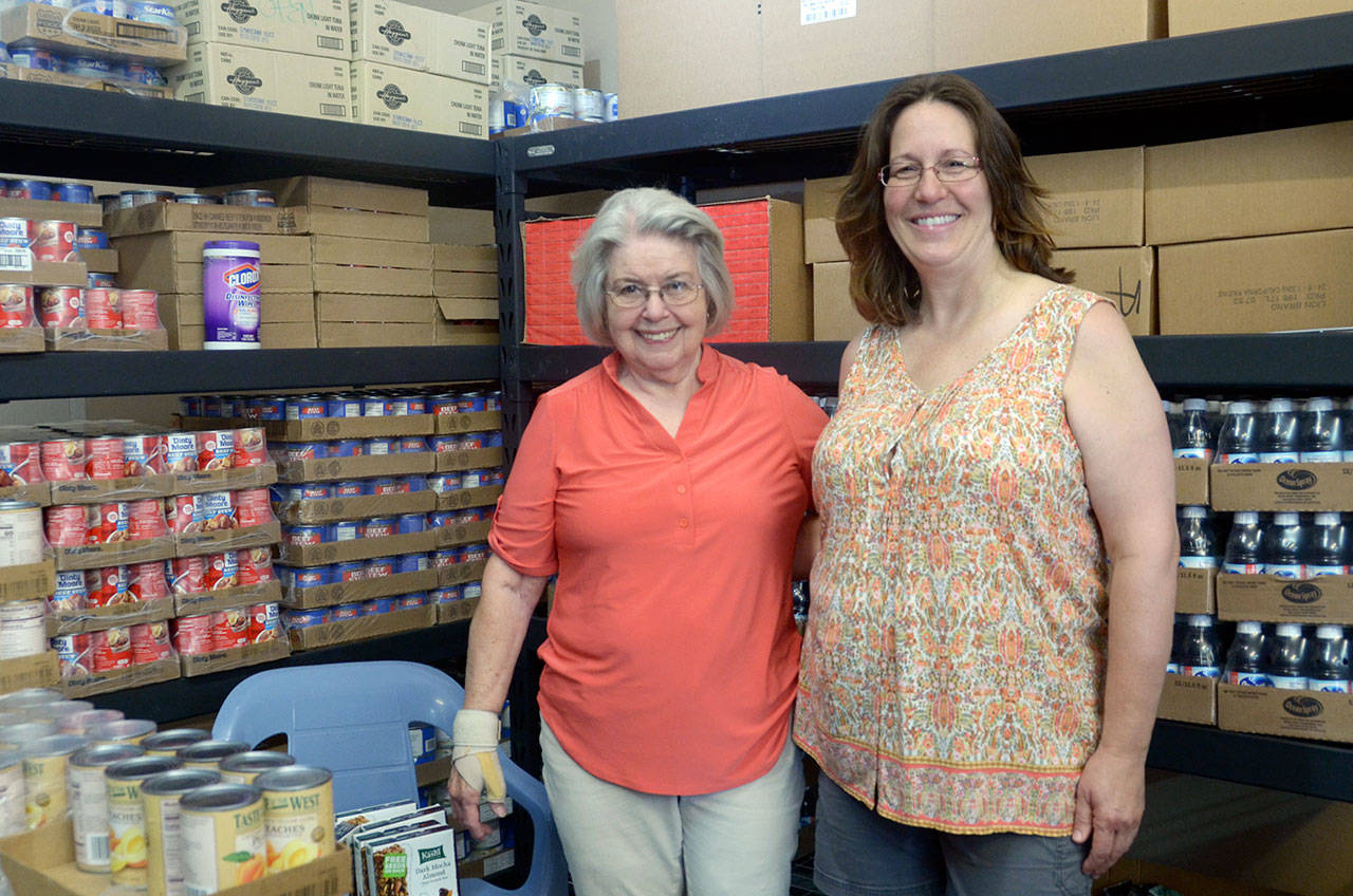 Volunteer Dorothy Rath and Tri-Area Food Bank manager Rachel Boock hand out cans of food at the new food bank location on Chimacum Road. (Cydney McFarland/Peninsula Daily News)