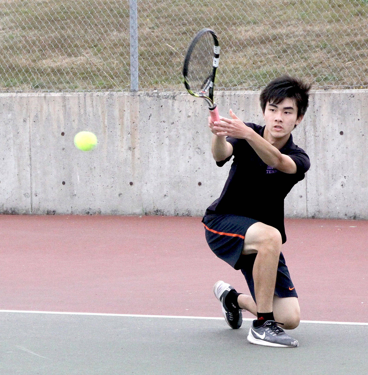 Raymond Lam of Sequim returns a volley from Port Angeles’ Kenny Soule in a rain-shortened meet Monday between the Wolves and Roughriders. (Dave Logan/for Peninsula Daily News)