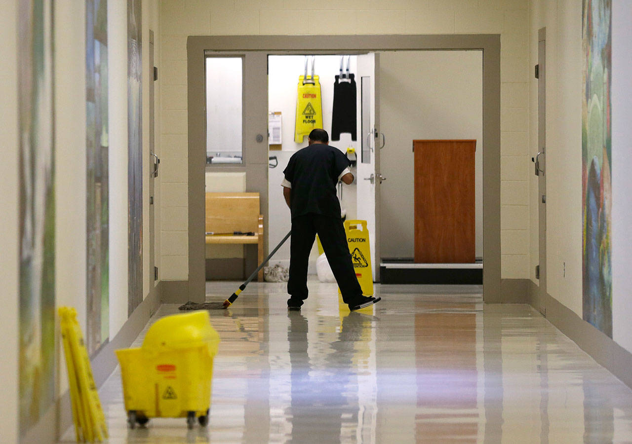 A detainee mops a floor in a hallway of the Northwest Detention Center in Tacoma during a media tour of the facility in June. (The Associated Press)