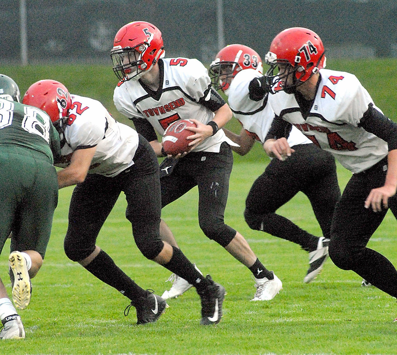 Keith Thorpe/Peninsula Daily News Port Townsend quarterback Noa Apker-Montoya, second from left, prepares to rush with the help of teammates, from left, Robert Hammett, Jacob Boucher and Jackson Foster earlier this month against Port Angeles.