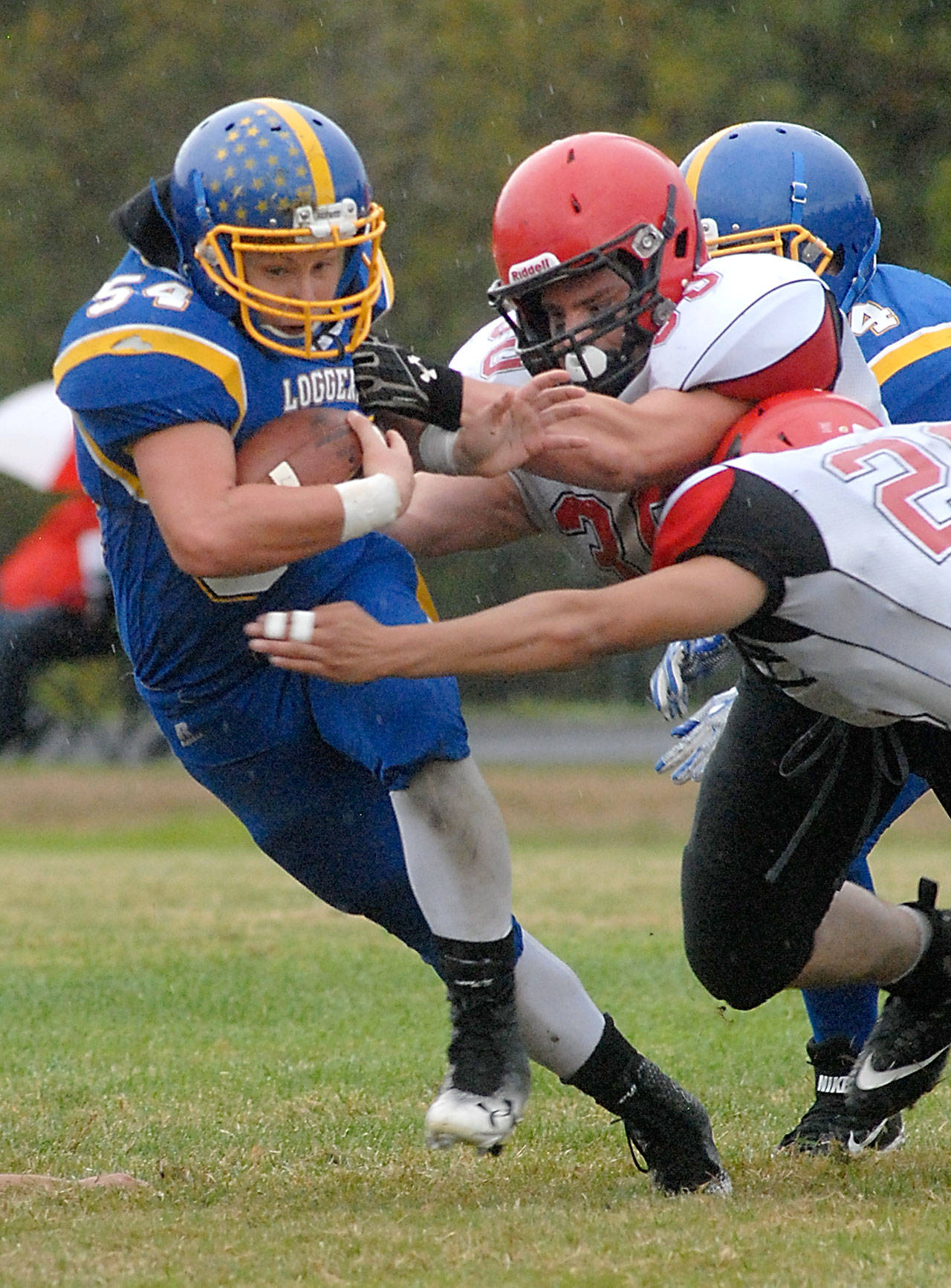 Keith Thorpe/Peninsula Daily News Crescent’s Noah Leonard, left, tries to elude the tackle of Neah Bay’s Danial Kilmer, center and Alan Tyler, right, after a block by Loenard’s teammate, Timothy Ward, rear, in the first quarter on Saturday in Joyce.