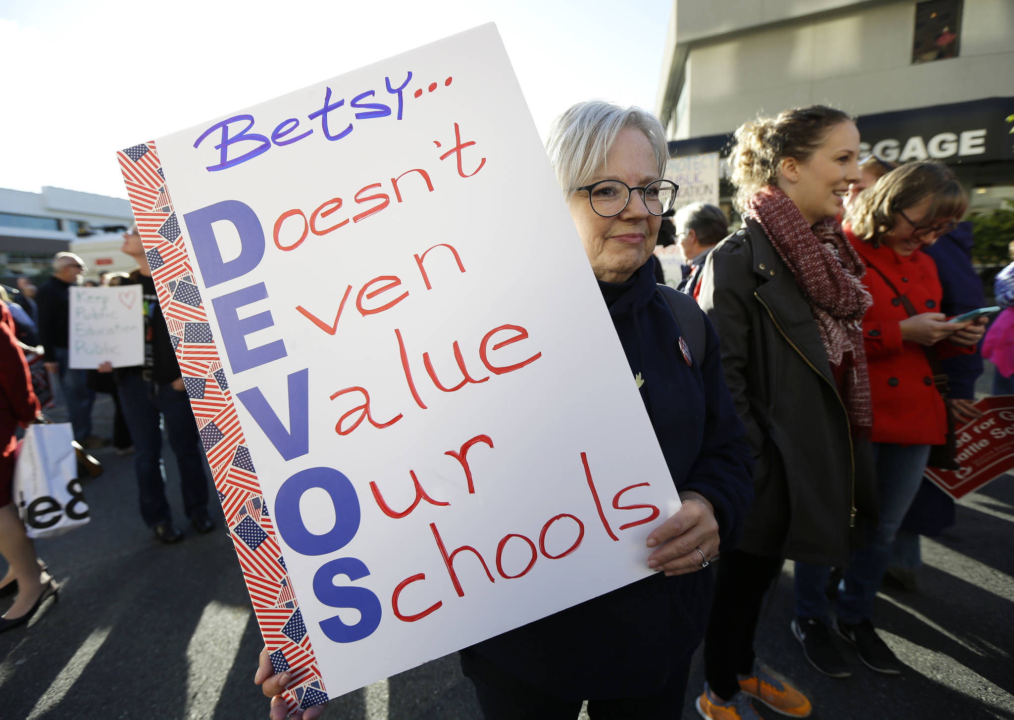 Colleen Webster of Renton holds a sign opposing U.S. Education Secretary Betsy DeVos on Friday outside the hotel where DeVos was scheduled to speak later in the evening in Bellevue. (Ted S. Warren/The Associated Press)