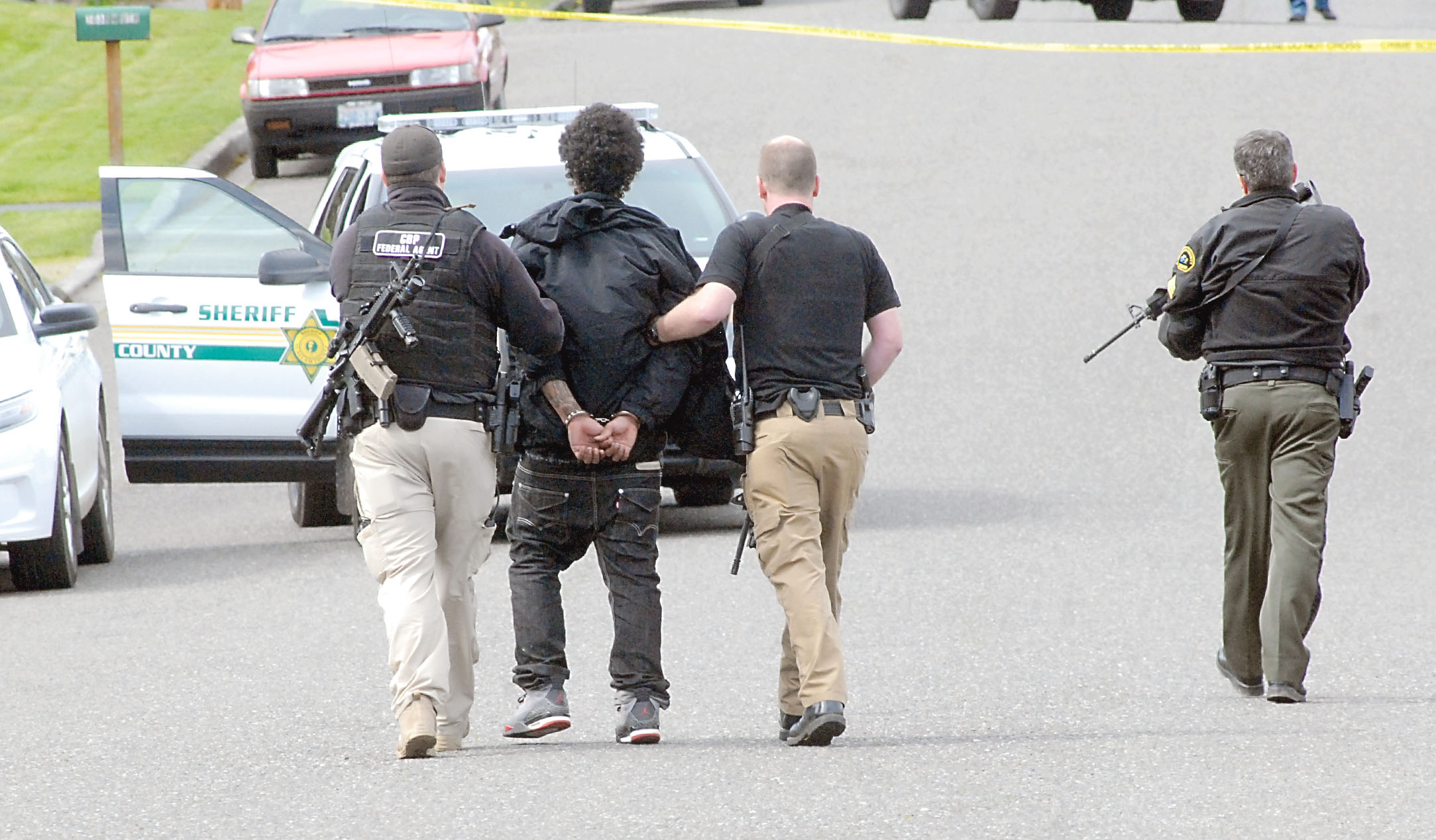 Law enforcement officers lead Ordez Kompkoff to a waiting patrol vehicle after he was arrested at a house on West Ninth Street in Port Angeles on Tuesday. (Keith Thorpe/Pennsula Daily News)