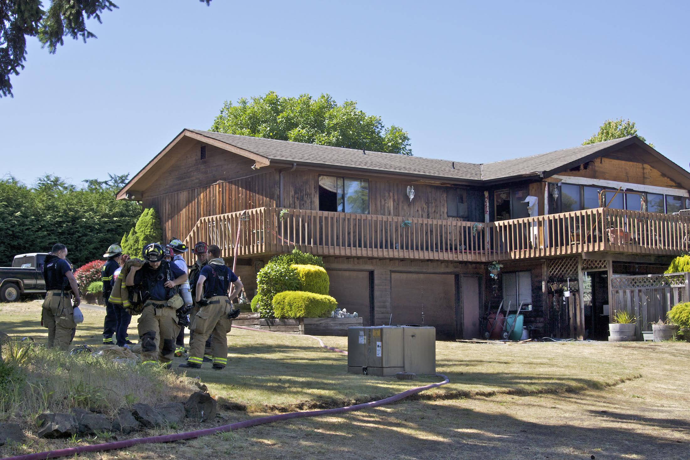 Firefighters confer after dousing a structure fire that occurred in the lower right unit of a house on 27th Street in Port Townsend this afternoon. (Steve Mullensky/for Peninsula Daily News)