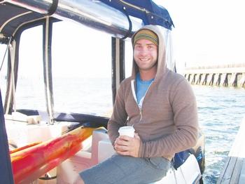 Andrew Malinak is pictured warming up aboard the Livin the Dream catamaran at Port Angeles' Boat Haven after cutting short his attempt to swim across the Strait of Juan de Fuca from Vancouver Island in July 2013. He will make a second attempt Sunday. Arwyn Rice/Peninsula Daily News