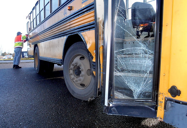 Port Angeles School District mechanic Mike Lundtedt secures the rear lift door on a school bus after it was struck near the front load door Wednesday morning. (Keith Thorpe/Peninsula Daily News)