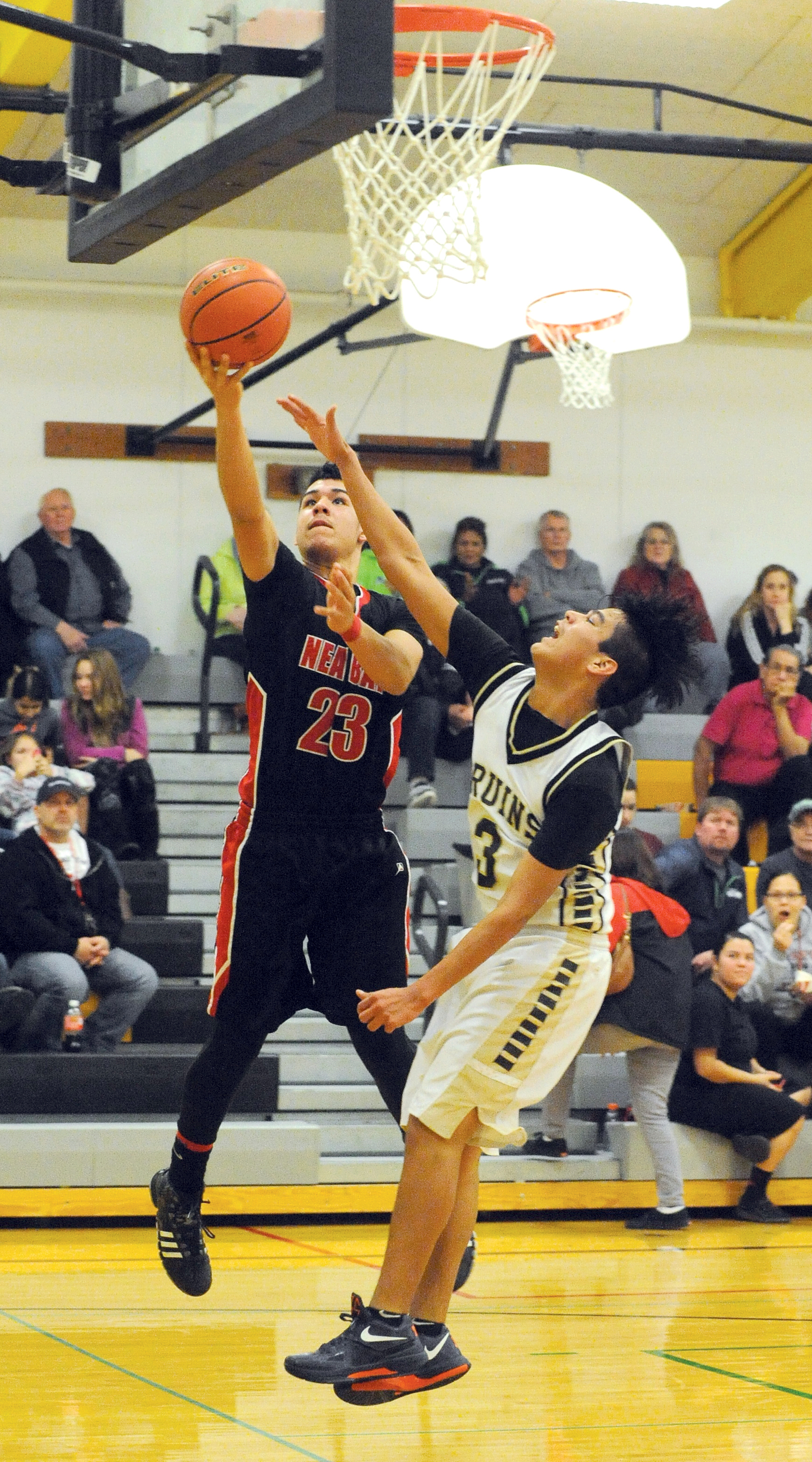 Neah Bay's Chris Martinez (23) lays the ball up over Clallam Bay's Alan Greene. (Lonnie Archibald/for Peninsula Daily News)