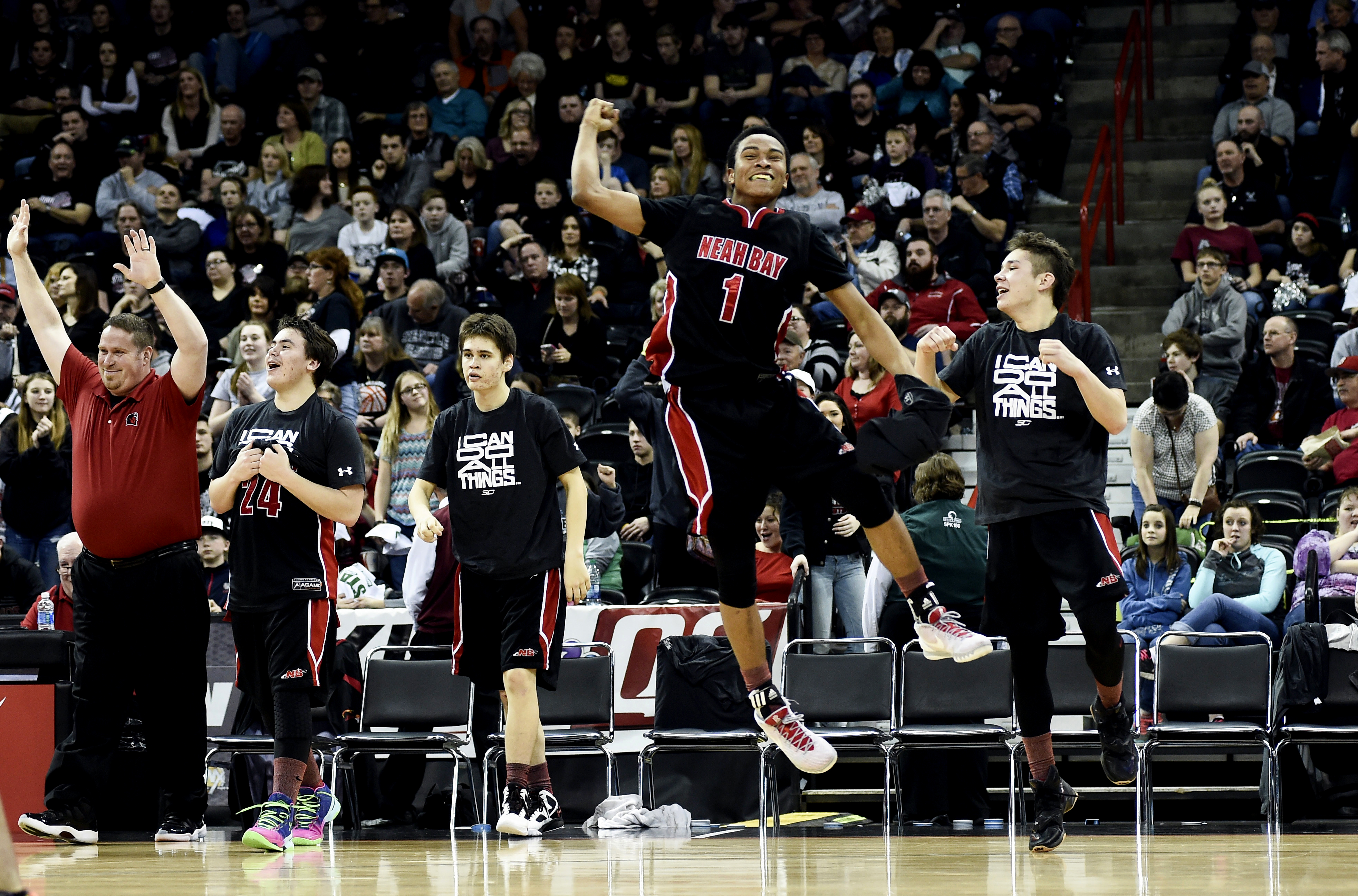 Neah Bay's Rwehabura Munyagi Jr. (1) leaps into the air in celebration after the Red Devils defeated Almira/Coulee-Hartline in the Class 1B state championship boys basketball game at Spokane Arena. Also part of the celebration are