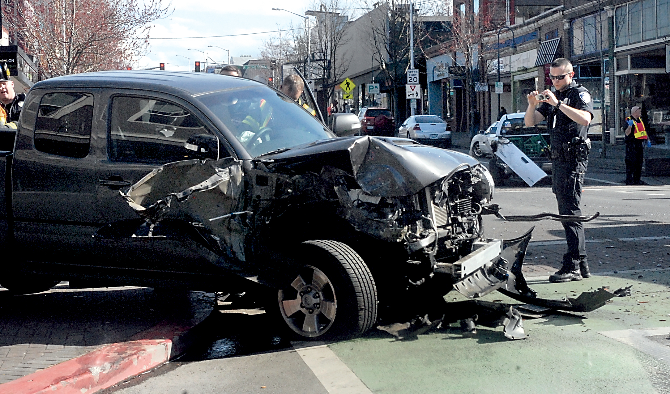 Port Angeles Police Officer Bruce Fernie photographs a pickup truck involved in rear-end collision with another pickup at the corner of First and Laurel streets in downtown Port Angeles on Thursday afternoon. (Keith Thorpe/Peninsula Daily News)