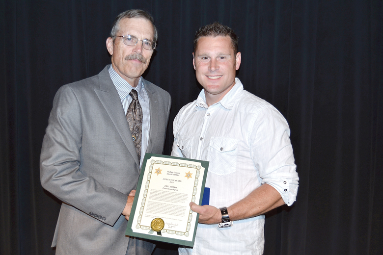 Clallam County Sheriff Bill Benedict presents Corrections Deputy Eric Morris with an award for helping to save the life of a Clallam County jail inmate. ()