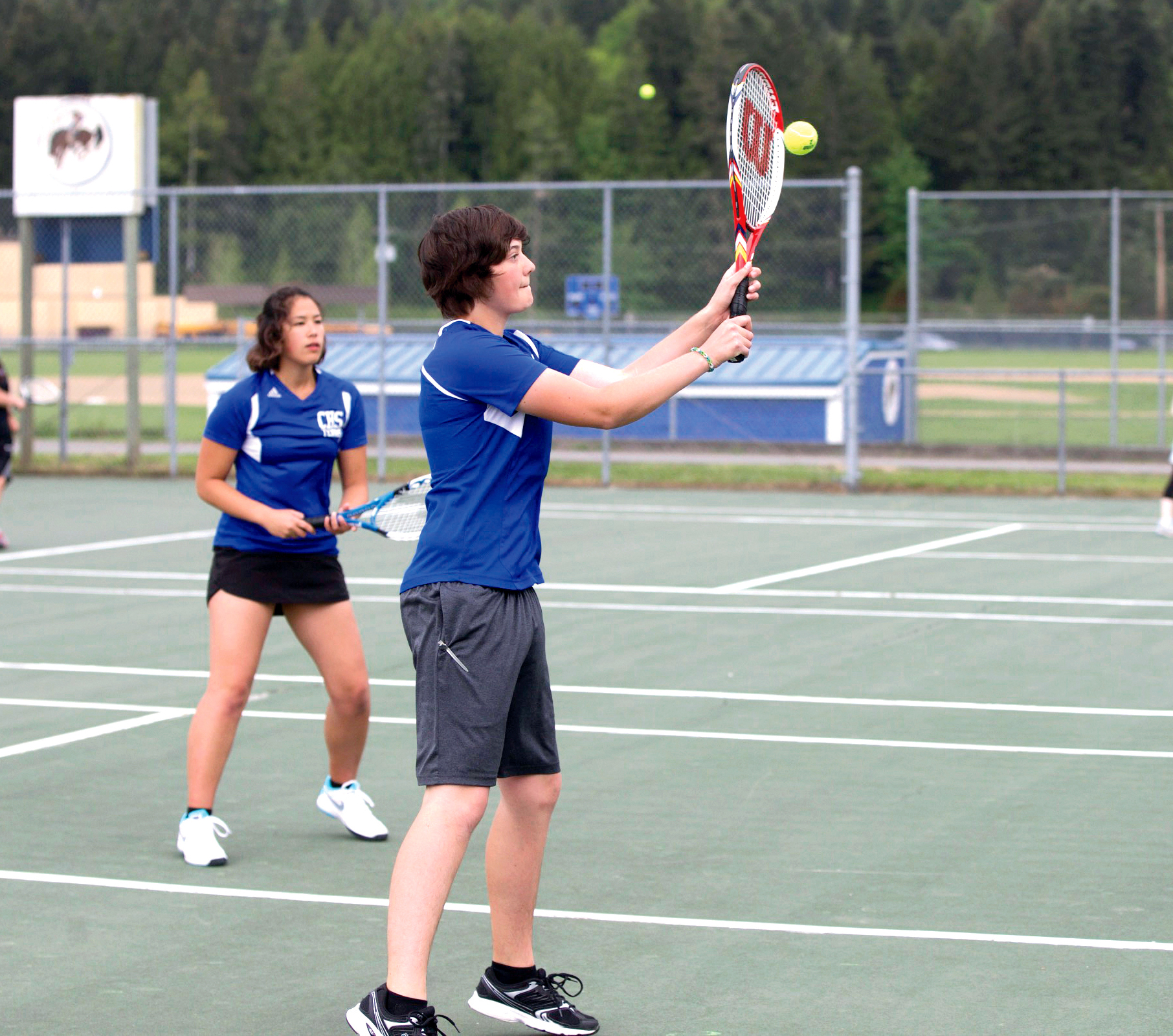 Chimacum's Ray Kaki returns a high volley as doubles partner Sarah Allen guards her alley during the Olympic League 1A tournament. (Steve Mullensky/for Peninsula Daily News)