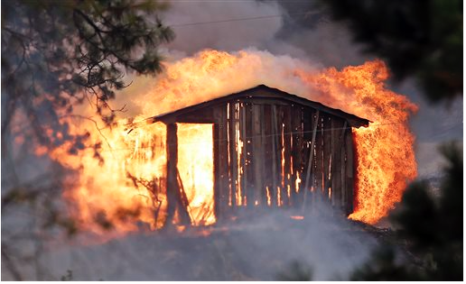 Flames pour from a structure fully engulfed in fire in a wildfire Friday afternoon in Tonasket. Out-of-control blazes in north-central Washington have destroyed buildings