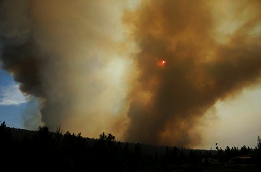 The sun appears orange due to a heavy smoke column as a wildfire flares up in the late afternoon near Omak on Thursday (Aug. 27). The Associated Press