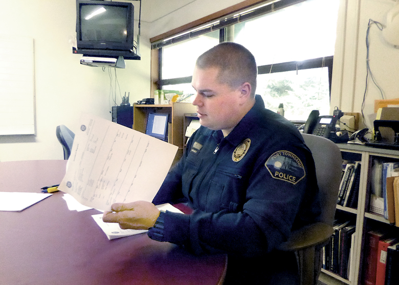 Port Townsend Police Detective Luke Bogues reads a report about a recent mental health-related police action. — Charlie Bermant/Peninsula Daily News ()